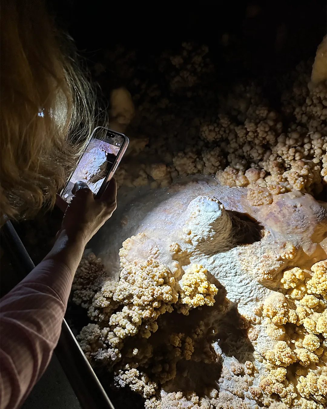 Femme prend une photo de cristaux de choux-fleurs dans la grotte Forestière