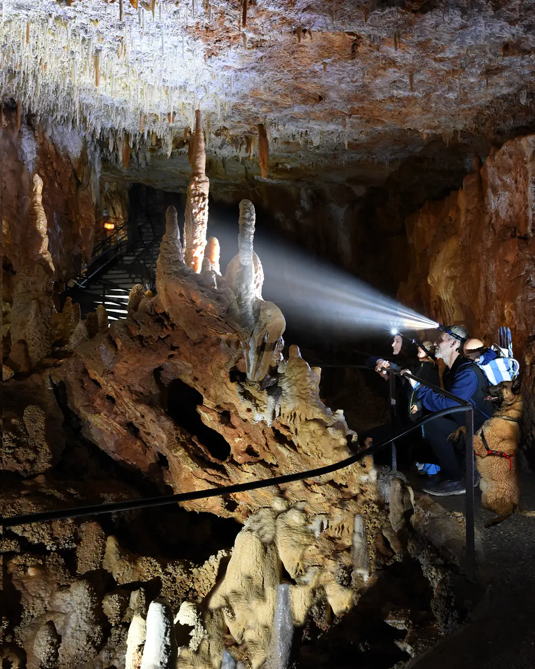 visiteurs avec les lampes frontales à l'entre de la grotte